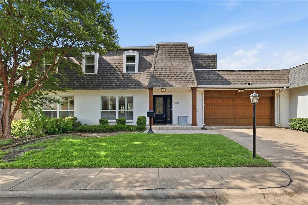 White exterior with a prominent brown shingle roof and dormer windows