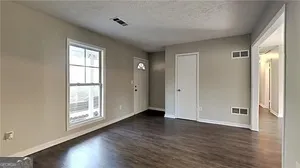 a view of an empty room with wooden floor and a window