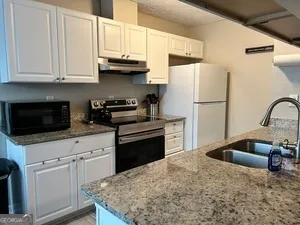 a kitchen with granite countertop a sink a stove and refrigerator