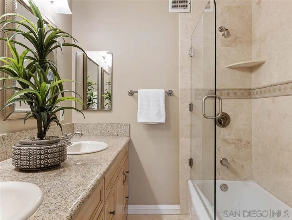 230 Prospect Street, Unit 17 La Jolla, CA 92037 - Photo 16 of 25 a bathroom with a granite countertop sink a mirror a potted plant and shower