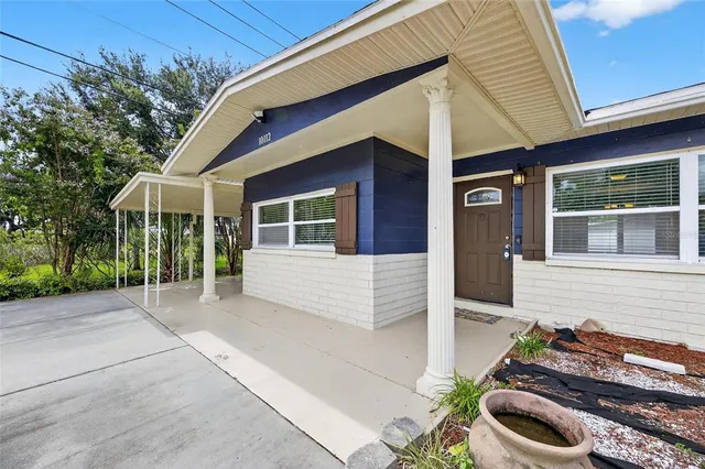 a front view of a house with chairs and plants