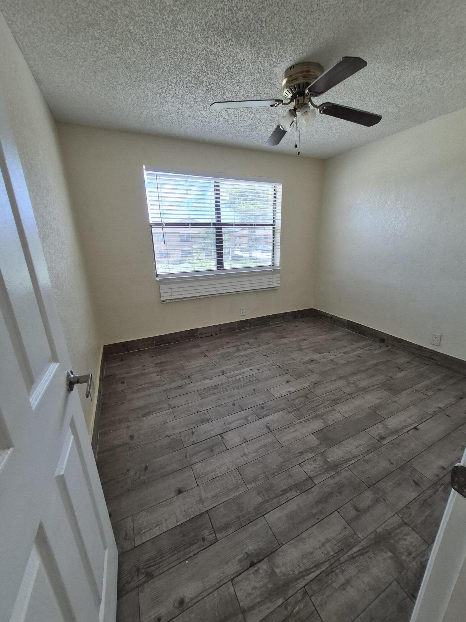 10039 Winding Lake Road, Unit 202 Sunrise, FL 33351 - Photo 11 of 14 wooden floor in an empty room with a window
