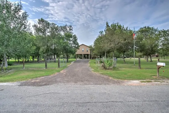 a view of a house with a big yard and a large trees