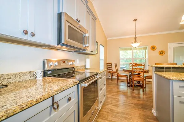 a kitchen with stainless steel appliances granite countertop a stove a sink and a wooden floors