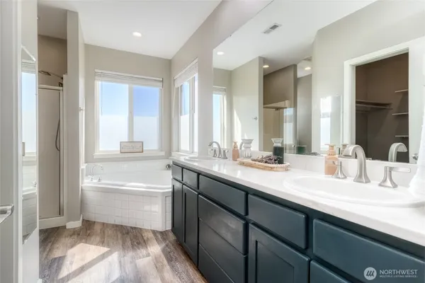 a bathroom with a double vanity sink a mirror and a bathtub
