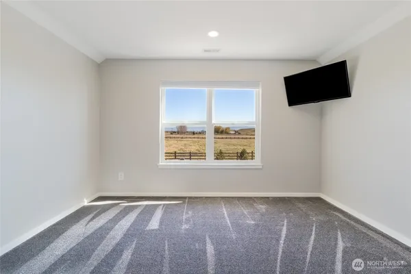 an empty room with a flat screen tv and windows