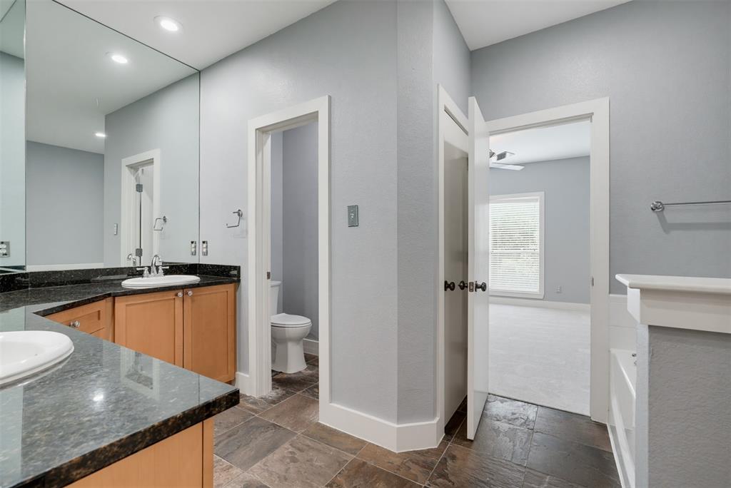 4830 Cedar Springs Road, Unit 30 Dallas, TX 75219 - Photo 25 of 32 Bathroom featuring a double vanity with stone countertops, wood cabinetry, and extensive wall mirror