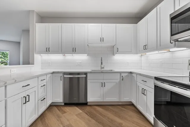 a kitchen with white cabinets white stainless steel appliances and sink