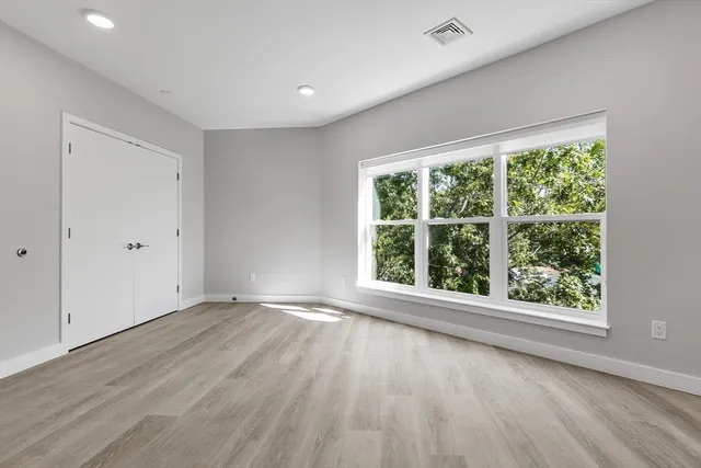 a view of an empty room with wooden floor and a window