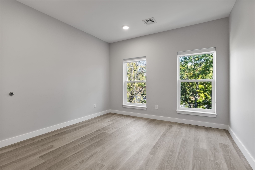 59 Mill Street, Unit 116 Woburn, MA 01801 - Photo 13 of 23 an empty room with wooden floor and windows