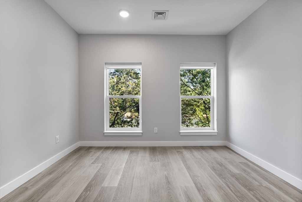 59 Mill Street, Unit 116 Woburn, MA 01801 - Photo 14 of 23 an empty room with wooden floor and windows