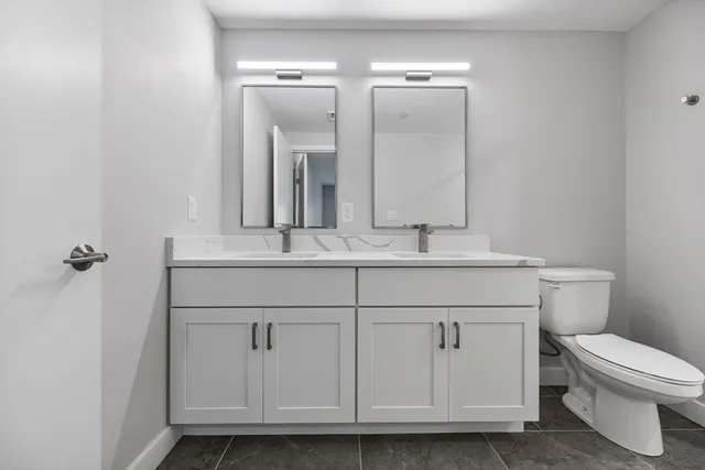 a bathroom with a granite countertop toilet sink and mirror