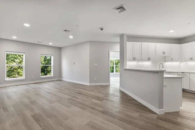 a kitchen with stainless steel appliances granite countertop a stove a sink and a refrigerator with wooden floors