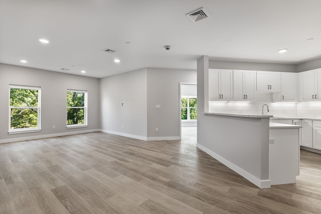 59 Mill Street, Unit 116 Woburn, MA 01801 - Photo 3 of 23 a kitchen with stainless steel appliances granite countertop a stove a sink and a refrigerator with wooden floors
