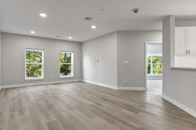 an empty room with wooden floor and windows