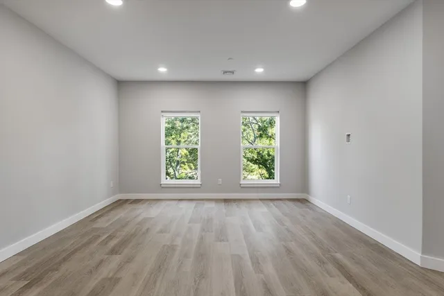 a view of an empty room with wooden floor and window