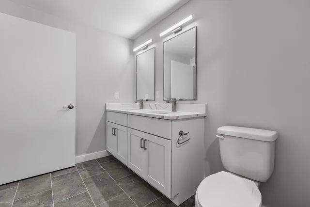 a bathroom with a granite countertop toilet sink and mirror