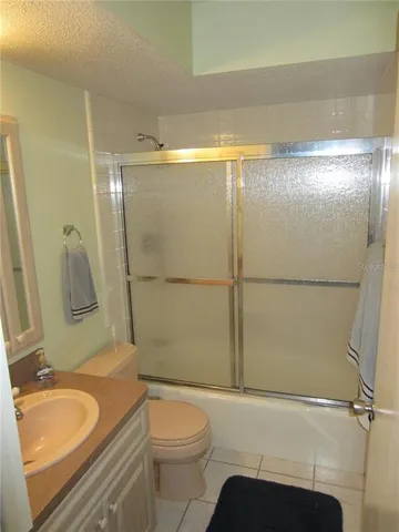 a bathroom with a granite countertop bathtub shower sink vanity and toilet