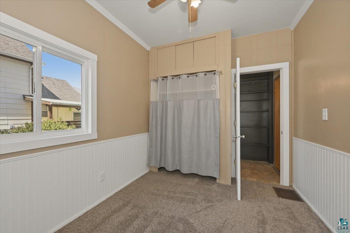 5319 East 3rd Street Superior, WI 54880 - Photo 15 of 33 Carpeted room featuring white wainscoting, an overhead ceiling fan, and a built-in storage area with a curtain