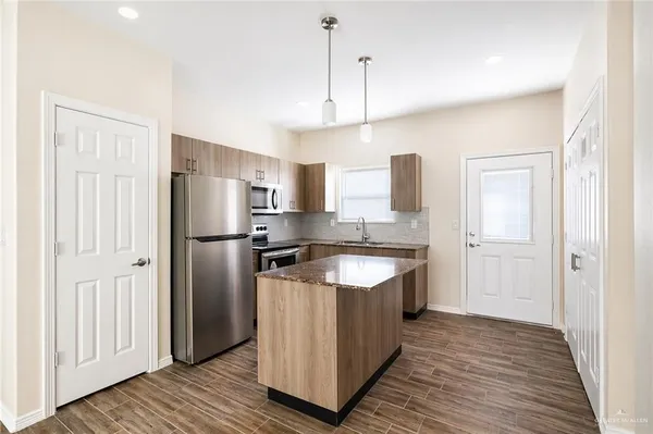 a kitchen with stainless steel appliances granite countertop a refrigerator a sink and wooden floor