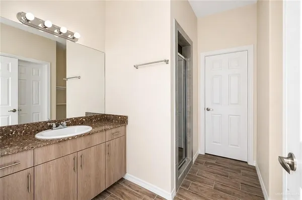 a bathroom with a granite countertop sink a mirror and a shower