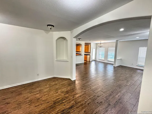 a view of an empty room with chandelier fan and fire place