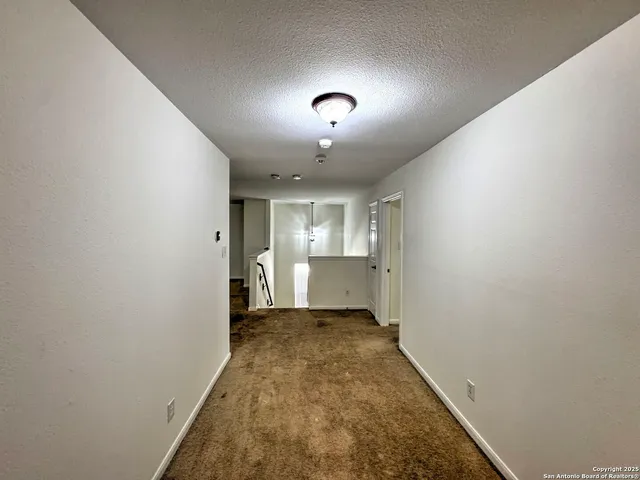 an empty room with a chandelier fan and windows