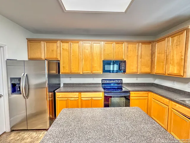 a kitchen with stainless steel appliances granite countertop a stove a sink refrigerator and microwave