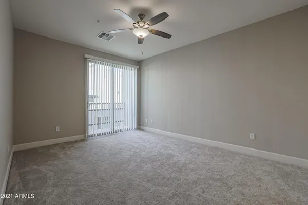 an empty room with chandelier fan and windows