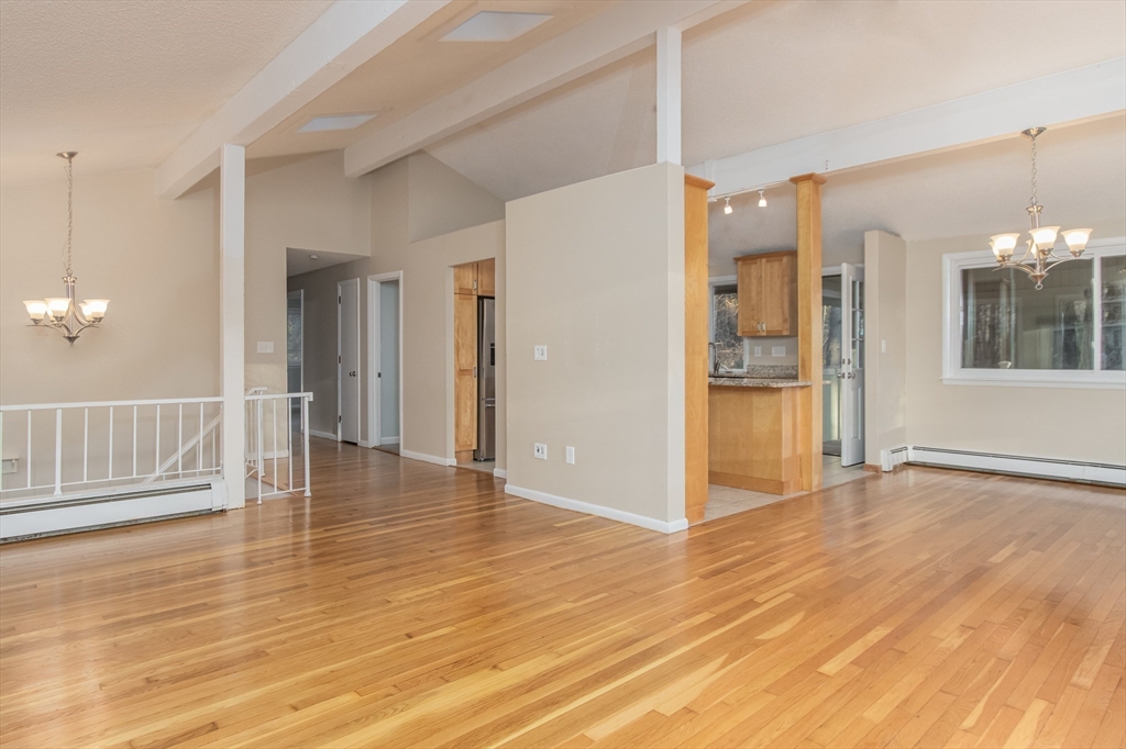 7 No Name Road Stow, MA 01775 - Photo 17 of 42 a view of an empty room with wooden floor and a kitchen
