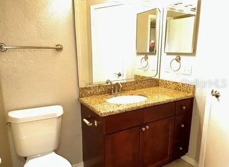 a bathroom with a granite countertop sink toilet and mirror