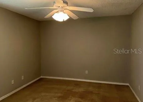 an empty room with a ceiling fan and carpet