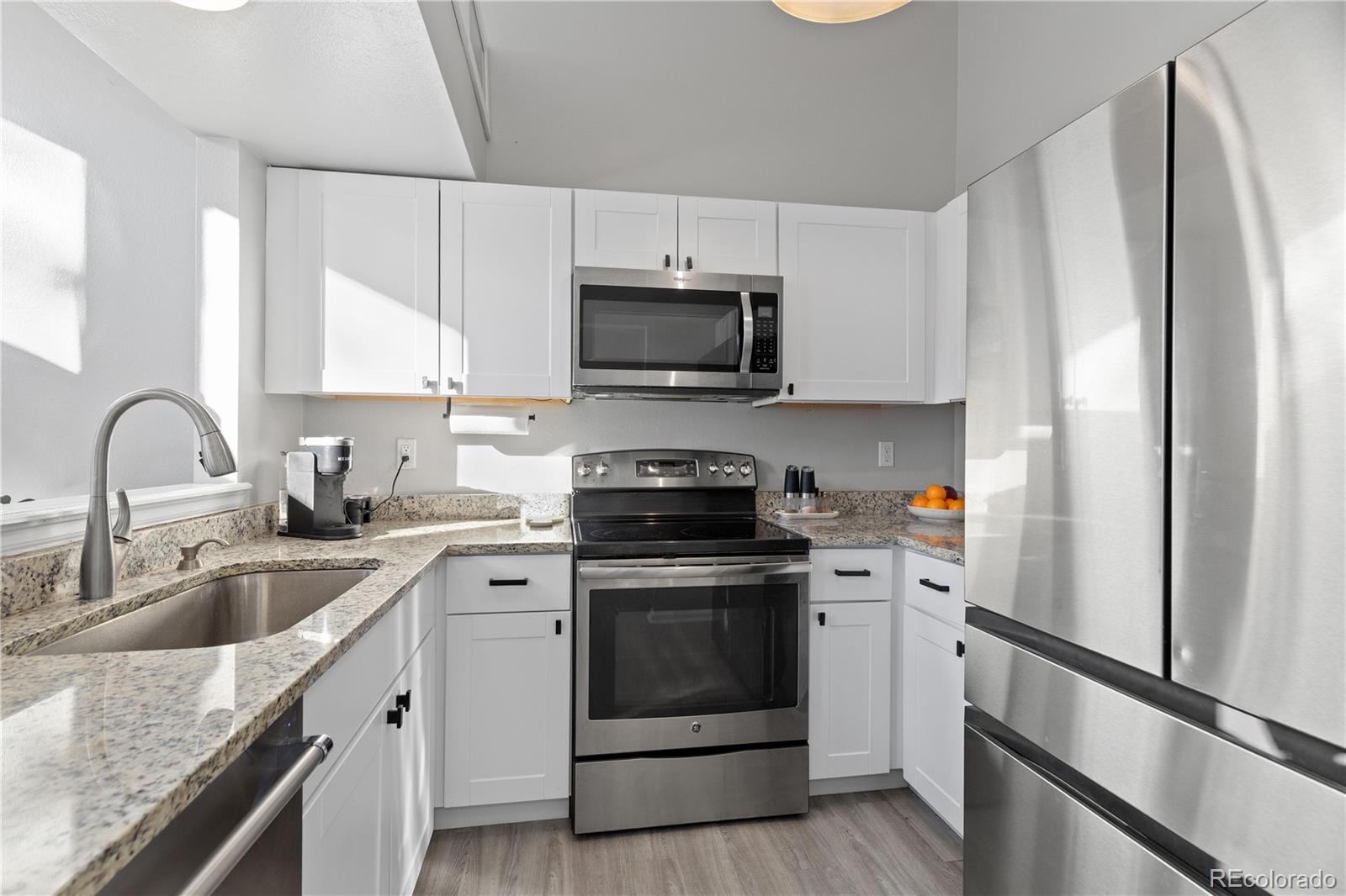 9364 Cattail Court Highlands Ranch, CO 80126 - Photo 11 of 31 a kitchen with granite countertop white cabinets and stainless steel appliances