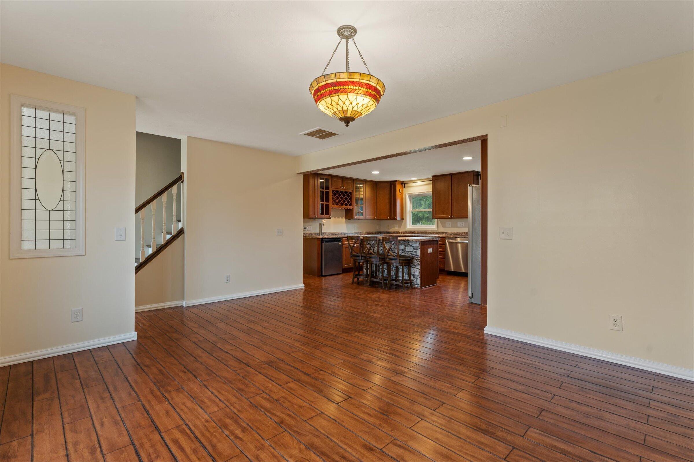 7692 North Emery Road Rolling Prairie, IN 46371 - Photo 7 of 69 a dining room with wooden floor a chandelier a glass table and chairs