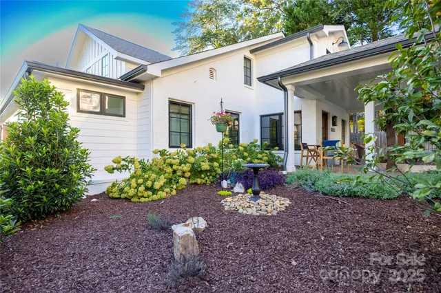 a view of a house with a yard and table and chairs under an umbrella