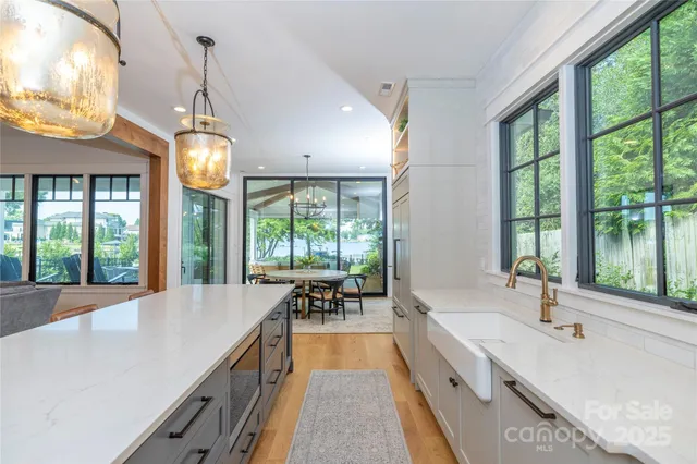 a large kitchen with kitchen island a large window cabinets a sink and stainless steel appliances