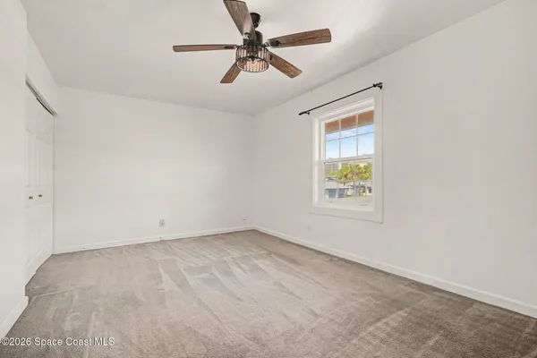 an empty room with windows and fan