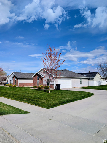 619 East 1st S Street, Unit S Preston, ID 83263 - Photo 2 of 16 Ranch-style exterior with brick and siding accents, featuring a two-car garage, concrete driveway, and a front yard with established landscaping