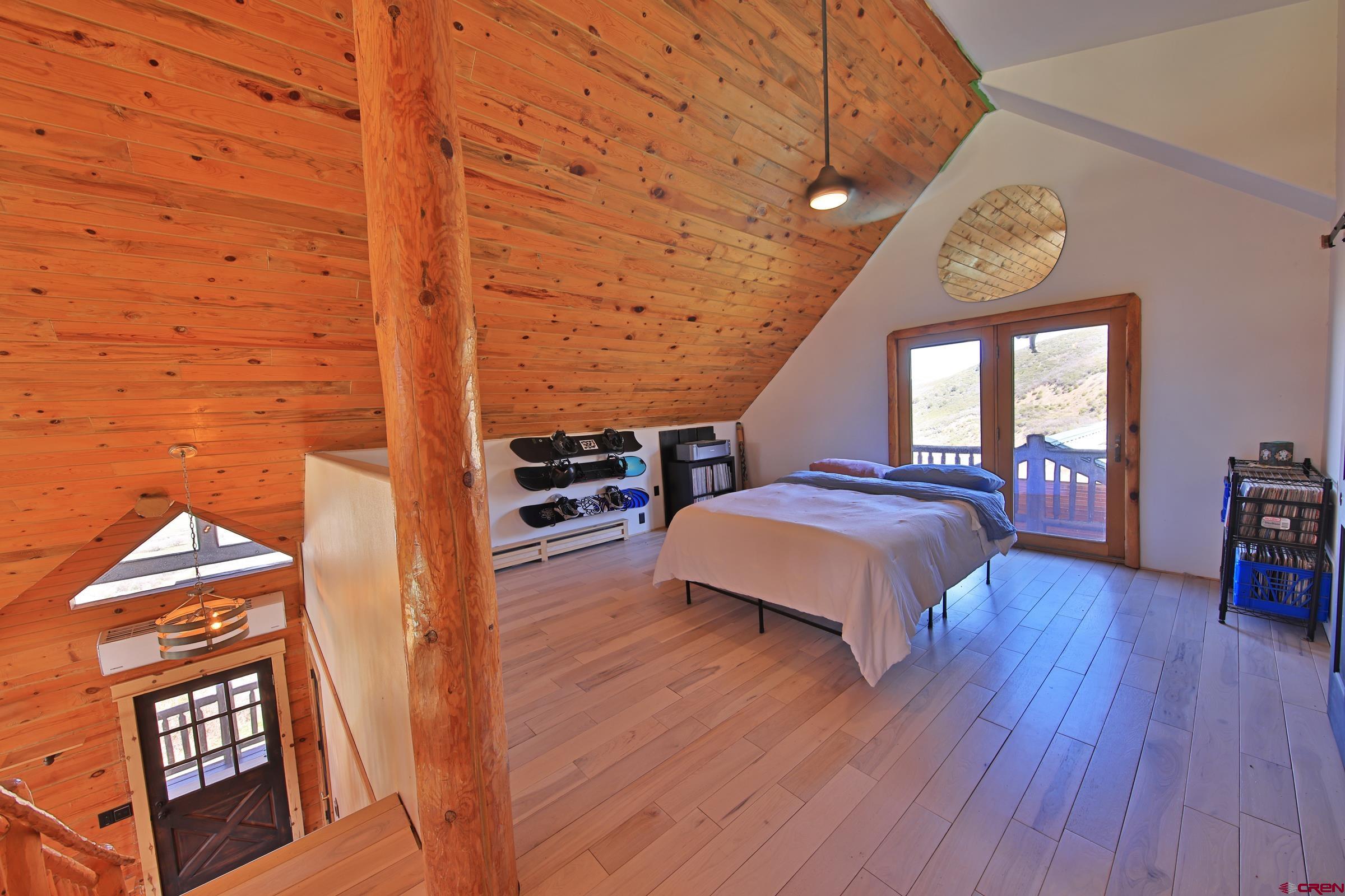 10822 60 75/100 Road Collbran, CO 81624 - Photo 19 of 45 a spacious bedroom with a bed and a table with wooden floor