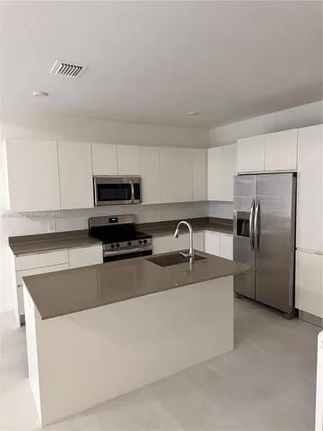 a kitchen with stainless steel appliances granite countertop a sink a refrigerator a stove a microwave and cabinets