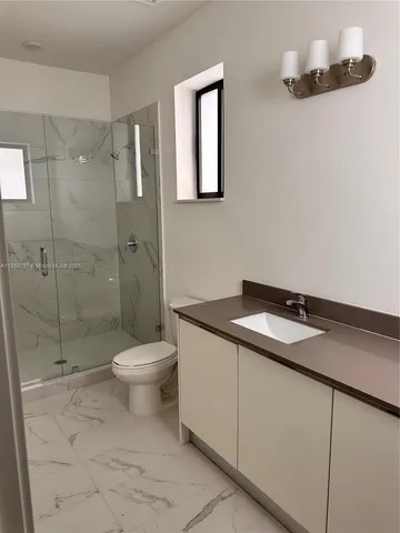 a bathroom with a granite countertop sink a toilet and shower