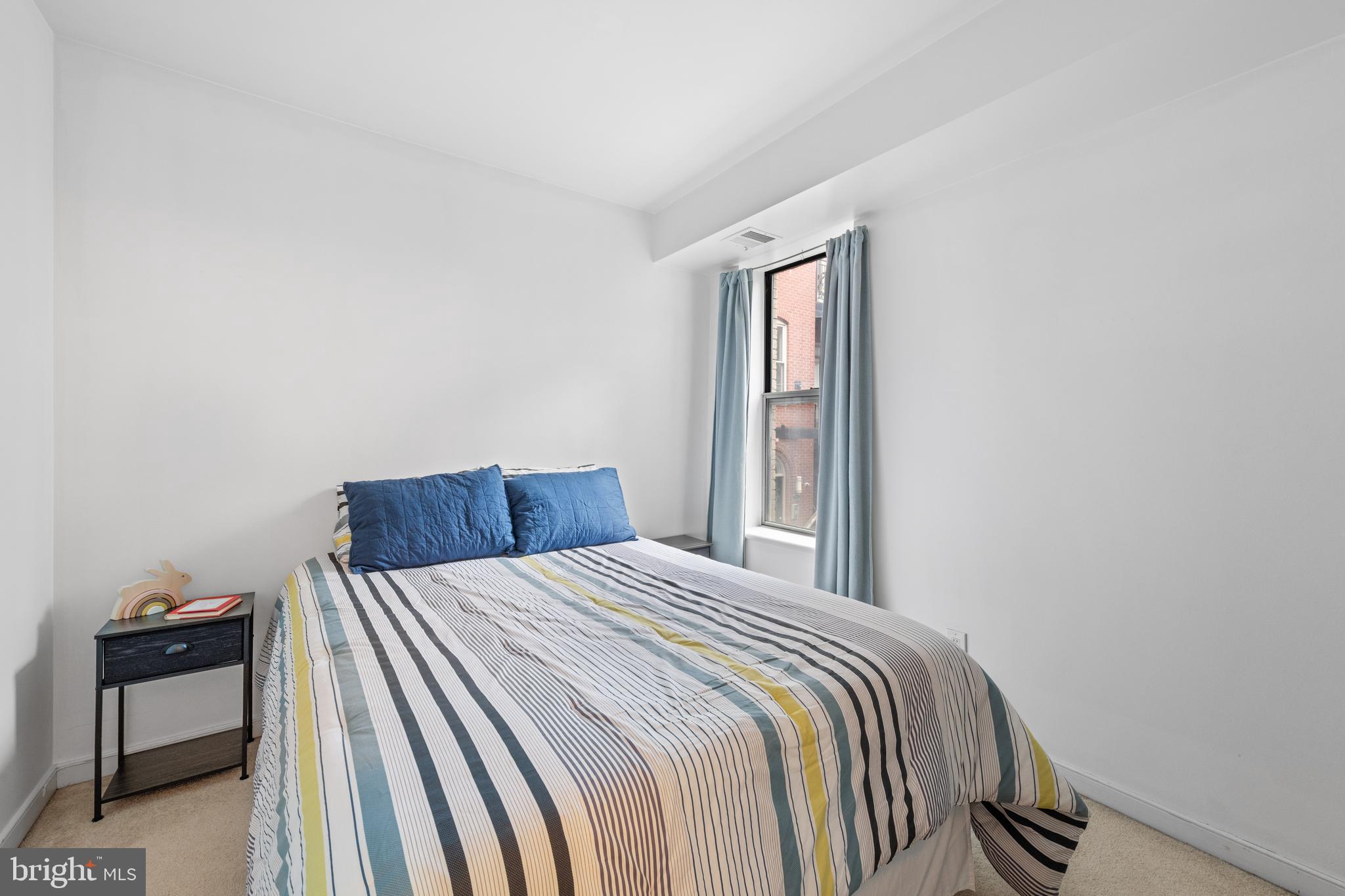 2611 Adams Mill Road Northwest, Unit 208 Washington, DC 20009 - Photo 16 of 22 a bed sitting in a bedroom next to a window