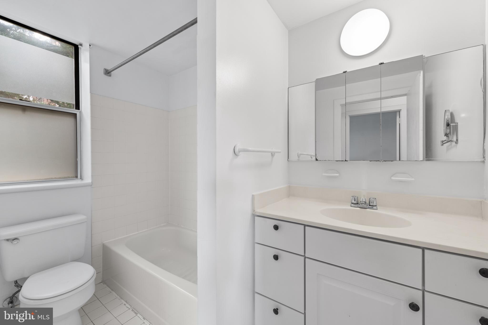 2611 Adams Mill Road Northwest, Unit 208 Washington, DC 20009 - Photo 20 of 22 a bathroom with a toilet a sink a tub and mirror
