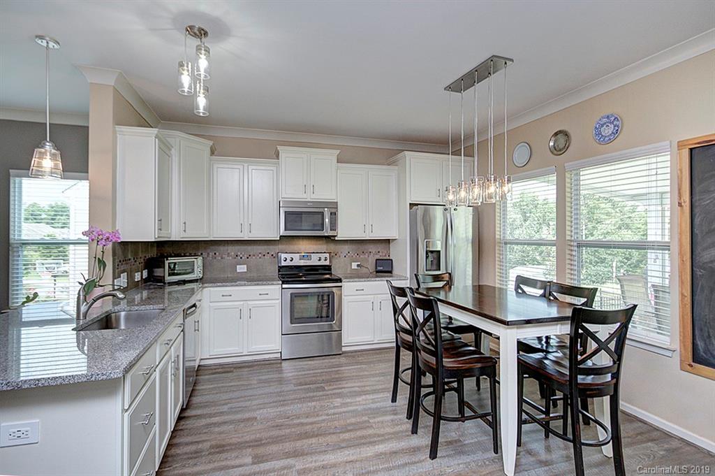 8008 Bryson Road Indian Land, SC 29707 - Photo 10 of 22 a kitchen with stainless steel appliances granite countertop a stove top oven a sink dishwasher a dining table and chairs with wooden floor