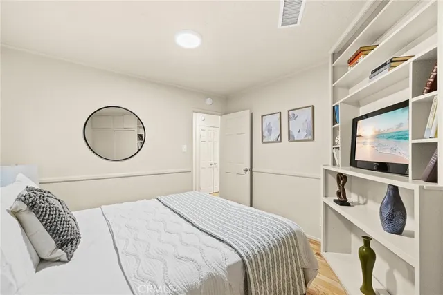 a bedroom with a bed a mirror and painting on the wall