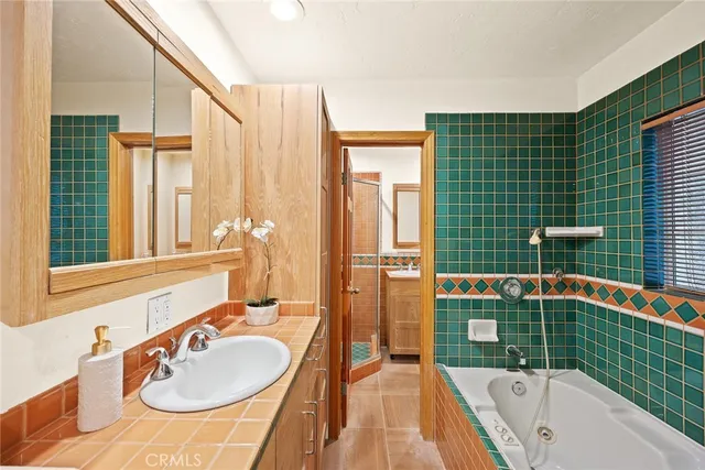 a bathroom with a sink and mirror with bathtub