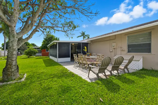 a view of a patio with table and chairs potted plants and large tree