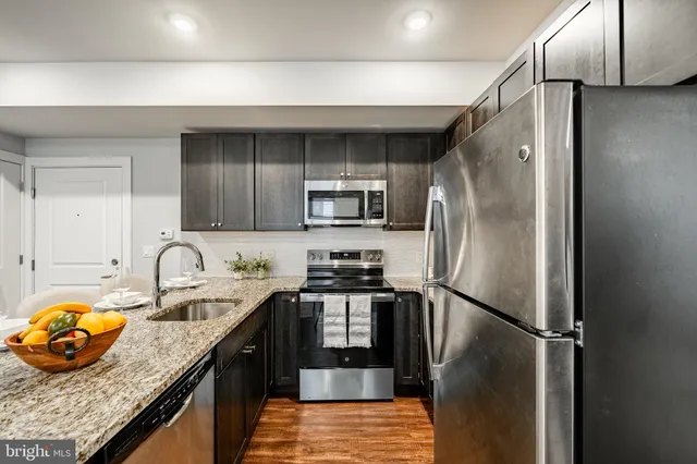 a kitchen with granite countertop a refrigerator and a stove top oven