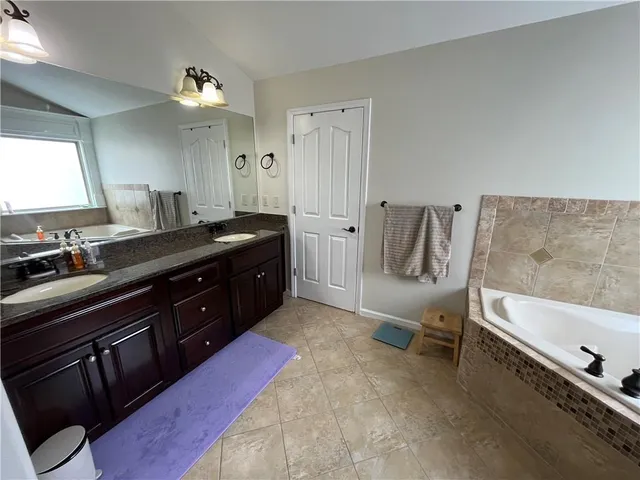 a spacious bathroom with a tub sink and mirror