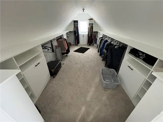 a view of walk in closet with clothes and shoes